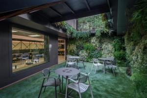 奥洛特Hotel Olot Centre的一个带桌椅的庭院和绿色的墙壁