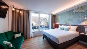 斯特拉斯堡voco Strasbourg Centre - The Garden, an IHG Hotel的一间卧室配有一张床、一张沙发和一个窗口