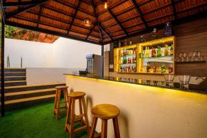安君纳De Lagom Comforts, Anjuna Beach的酒吧设有2张凳子和1个带饮品的吧台