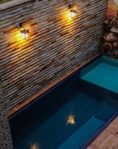戈亚斯州上帕莱索Pousada Araras的砖墙上灯的游泳池