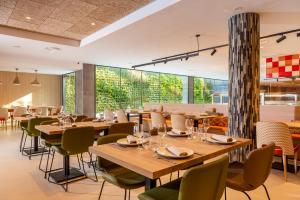 罗列特海岸L'Azure Hotel 4* Sup的餐厅设有木桌和椅子以及大窗户。