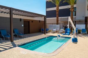 拉斯维加斯Candlewood Suites - Las Vegas - E Tropicana, an IHG Hotel的大楼前的游泳池,带椅子和滑梯