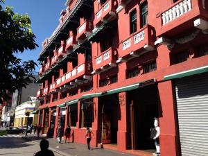 危地马拉皇宫酒店的一座红色的建筑,前面的人在行走