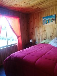 黑岛Cabañas Tu Bosque的一间卧室配有一张带紫色毯子的床和窗户。