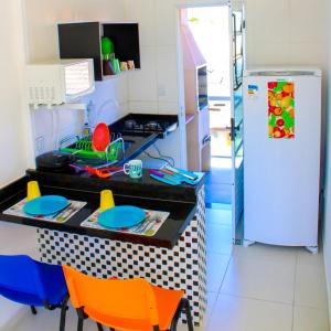 伯迪亚哥Kitnet Maitinga的厨房配有带椅子的柜台和冰箱。