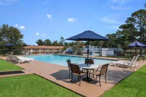 基尔戈Motel 6-Kilgore, TX的游泳池旁配有遮阳伞的桌椅
