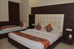 阿姆利则Hotel KK Continental 50 Meter from Railway Station - Amritsar的酒店客房配有两张带色彩缤纷枕头的床。