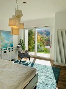 普福尔茨海姆Apartment Am Kupferhammer的一间卧室设有一张婴儿床、一把椅子和一个大窗户。