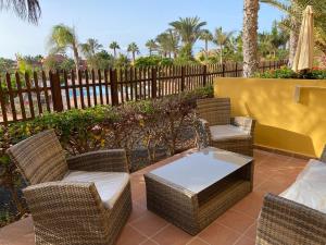 科拉雷侯Oasis Fuerteventura Beach Apartments的庭院设有藤椅、桌子和围栏