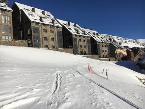 帕斯底拉卡萨Lux Isard "Acceso directo a pistas"的雪地中建筑物前面的滑雪场