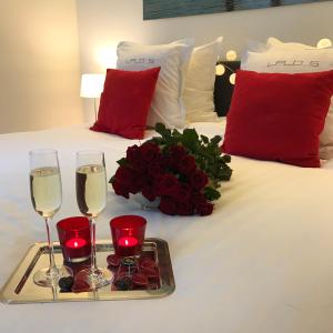 奥斯坦德利奥波德5豪华设计公寓的一张带两杯葡萄酒和一盘玫瑰的床铺