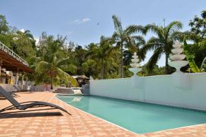 蒙特哥贝Chateau Margarita JA的度假村的游泳池,设有躺椅和椰子树