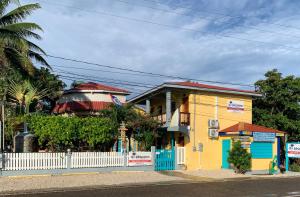 霍普金斯All Seasons Belize的黄色和蓝色的房子,有白色的栅栏