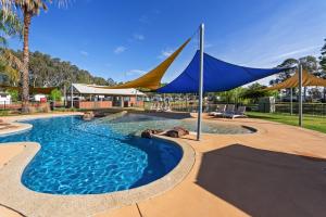 莫阿马Discovery Parks - Maidens Inn Moama的一个带蓝色和黄色遮阳伞的游泳池