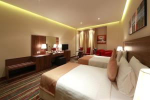 迪拜Al Khaleej Palace Deira Hotel的酒店客房配有两张床和一张书桌