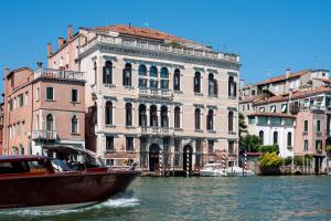 威尼斯Ca' dei Cuori on the Grand Canal的船在水中,在建筑物前