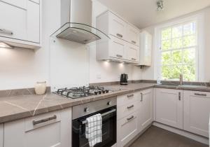 爱丁堡老城区城堡套房3号公寓的厨房配有白色橱柜和炉灶烤箱。