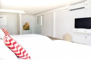 坎昆Villas Marlin 108, a pie de playa, albercas, jacuzi, ubicacion inmejorable的白色卧室配有床和平面电视