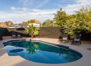 凤凰城Phoenix Arcadia Turney home的庭院内的游泳池配有椅子和遮阳伞