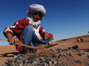 瓦尔扎扎特达尔法哈娜住宿加早餐旅馆的坐在沙漠中一堆岩石上的人
