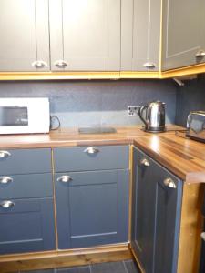 基德明斯特Charming Spacious Apartment, Kidderminster的厨房配有蓝色橱柜和微波炉