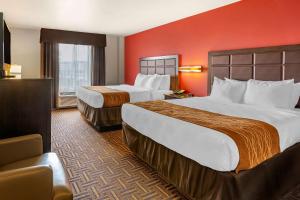 迈诺特Sonesta Essential Minot的红色墙壁的酒店客房内的两张床
