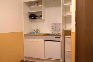 东京上野之家Vip家庭房的厨房配有白色橱柜和洗碗机。