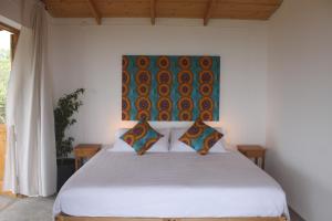 圣菲利佩La Fora Ecolodge的卧室配有一张白色床,墙上挂有绘画作品