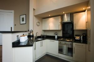 爱丁堡哈丁顿广场公寓的厨房配有白色橱柜和黑色台面