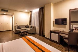 雅加达Oria Hotel Jakarta的一间配备有沙发及电视的酒店客房