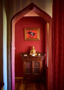 Mount TomahTomah Retreat - Studio CHILL with fireplace and clawfoot bath的一间设有红色墙壁和一张桌子及雕像的房间