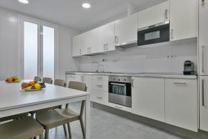 巴塞罗那巴塞罗那在一起公寓的白色的厨房,配有桌子和一碗水果