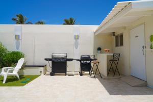棕榈滩Yoyita Suites Aruba的白色墙壁前带烧烤架和椅子的天井