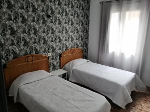 大加那利岛拉斯帕尔马斯阿卡拉瓦内拉斯青年旅舍的一间卧室设有两张床,墙上贴有壁纸。