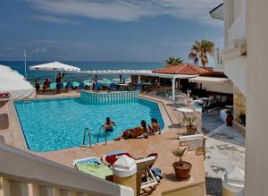 阿德里安诺斯坎波斯Jo An Beach Hotel的度假村的游泳池,人们坐在椅子上
