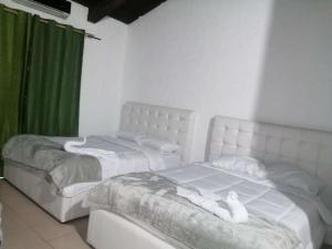 PotrerillosCasona del Valle的配有绿窗帘的客房内的2张白色床