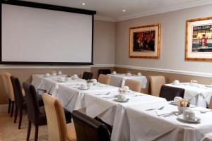伦敦贝斯特韦斯特日冕酒店的一间设有桌子和大屏幕的会议室