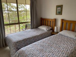 克莱尔Windmill Cottage的一间卧室设有两张床和大窗户