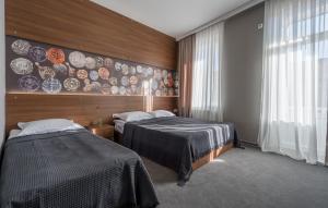 西格纳吉Hotel History • სასტუმრო ისტორია的墙上挂有盘子的房间的两张床