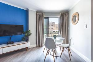 开普敦The Paragon KAHLÚA Modern Open Plan Centrally Located的客厅设有蓝色墙面和桌椅