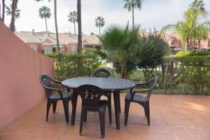 奇克拉纳－德拉弗龙特拉Apartamento Pink Mariposas的棕榈树庭院里的一张桌子和四把椅子