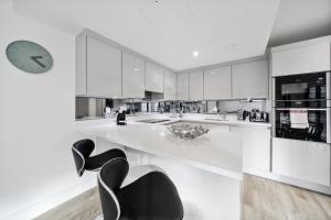 伦敦Executive Apartments in Bermondsey FREE WIFI & AIRCON by City Stay Aparts London的一间白色的大厨房,配有黑色的椅子和时钟