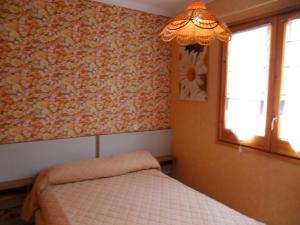 莱斯卡拉Holiday Home Josiane by Interhome的一间卧室设有一张床、一个窗户和一个吊灯。