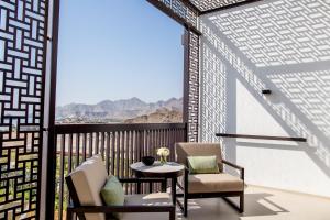 艾阿卡InterContinental Fujairah Resort, an IHG Hotel的阳台配有2把椅子和1张桌子,享有风景。