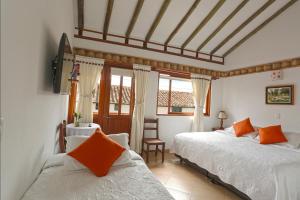 莱瓦镇天使别墅酒店的一间卧室配有两张带橙色枕头的床