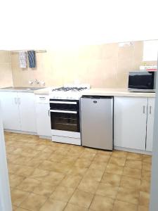 芒特甘比尔Limestone Coast Tourist Park的厨房配有白色橱柜和炉灶烤箱。
