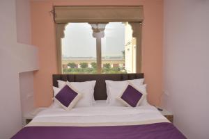斋浦尔Hotel Siddharsh Heritage的窗前带紫色和白色枕头的床