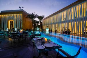 吉达Vivienda Hotel Villas, Jeddah的游泳池旁的餐厅配有桌椅