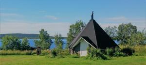 耶利瓦勒Piilijärvi Camping的一座小教堂,位于一个有湖泊的田野上