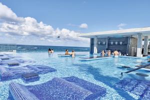 拿骚Riu Palace Paradise Island - Adults Only - All Inclusive的一群人在靠近海洋的游泳池里